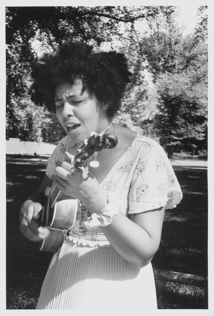 Young Woman Playing Ukulele and Singing Hymns in Central Park